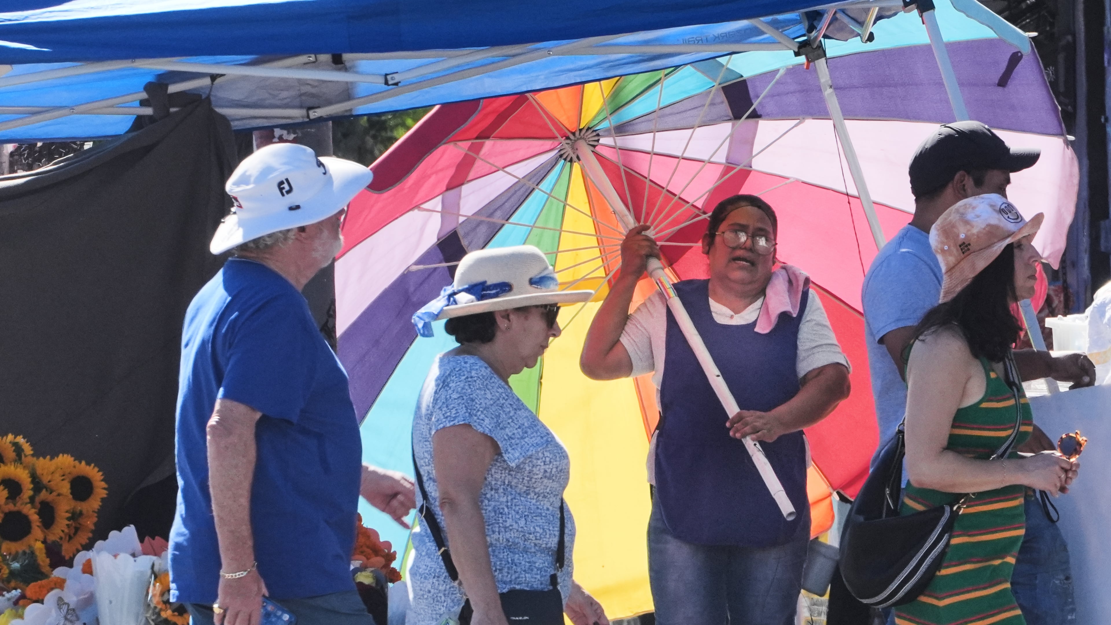 A street vendor uses an umbrella to shelter from the sun on a unseasonably hot day Tuesday, Oct. 28, 2025, in Los Angeles. (AP Photo/Damian Dovarganes)