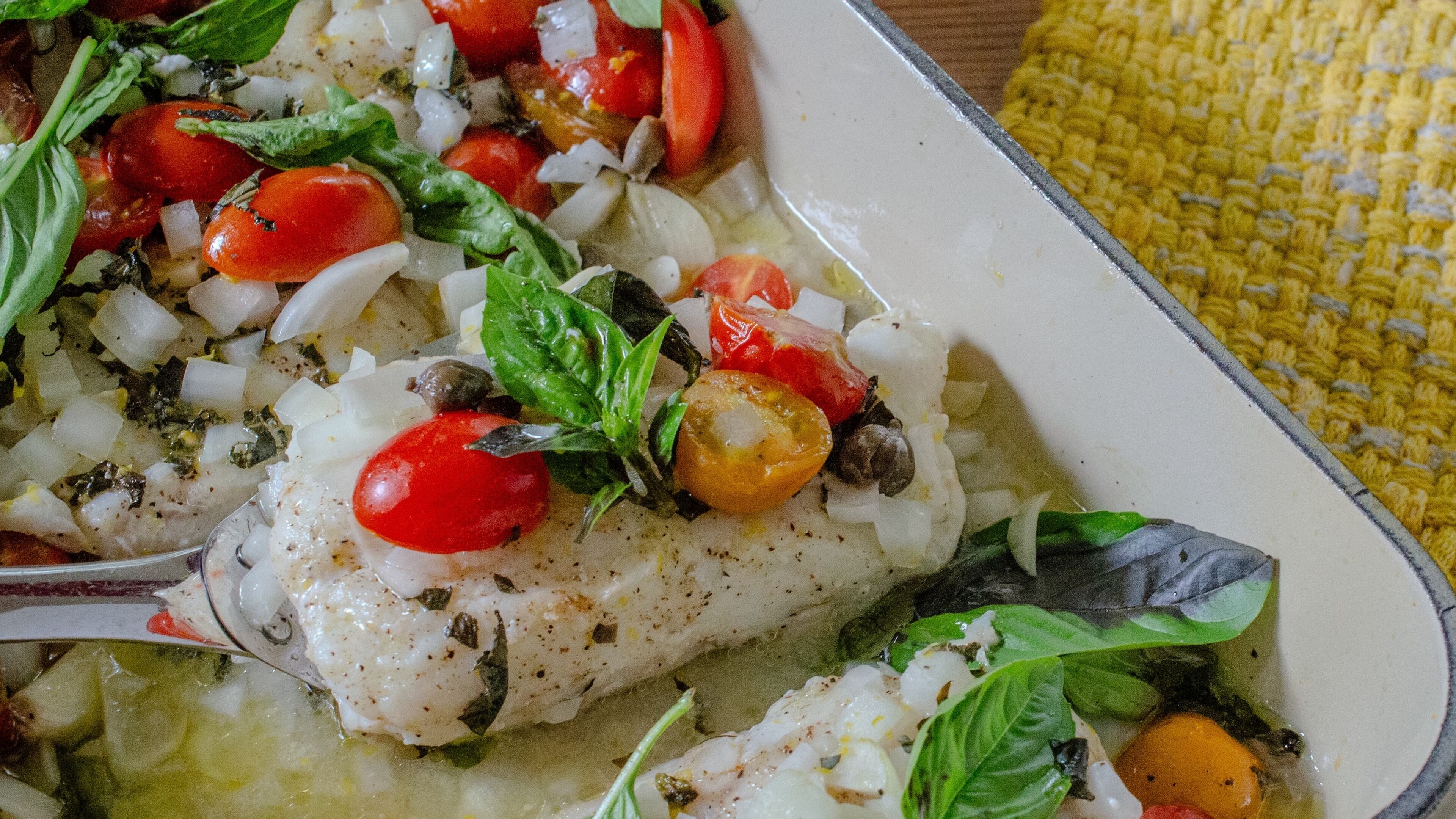 Fish fillets are baked with cherry tomatoes, capers, lemon and basil for an easy and satisfying seafood supper. (Virginia Willis for the AJC)