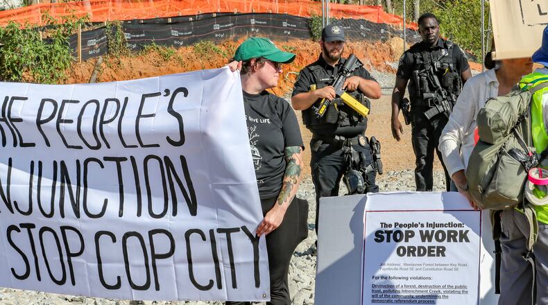 September 7, 2023 DeKalb County: Protesters gathered on Constitution Road (shown here) after five individuals were arrested Thursday morning, Sept. 7, 2023 at the site of Atlanta’s proposed public safety training center after chaining themselves to construction equipment in an effort to halt work. According to the Atlanta Police Department, the training center opponents broke into the construction site off Constitution Road around 9:30 a.m. Thursday. “Those 5 people have been taken into custody and we are working with the Georgia Bureau of Investigation regarding charges on these individuals,” the department said in a statement. About two dozen protesters also lined the site in unincorporated DeKalb County, east of Atlanta, in opposition to the 85-acre facility. They chanted “Cop City will never be built” as law enforcement officers amassed. The crowd called the effort “the people’s injunction” to halt construction. “We have tried to get justice in the courts, we have tried to get justice using our politicians, and unfortunately, they have betrayed and failed us,” said Mary Hooks, with the activist group Movement for Black Lives. “So when our government systems fail, that is when the people must stand up and take action.” The demonstration comes just days after more than 60 anti-training center activists were indicted on racketeering and other charges over the ongoing clash between the city and facility opponents. The indictment mainly focuses on the Defend the Atlanta Forest group, with prosecutors describing it as an “anti-government, anti-police, and anti-corporate extremist organization.” The indictment, handed up by a Fulton County grand jury, is being prosecuted by the Georgia Attorney General’s Office. “Anytime somebody puts their bodies on the line for the cause,” said Hooks, “it was worth the risk.” (John Spink / John.Spink@ajc.com)