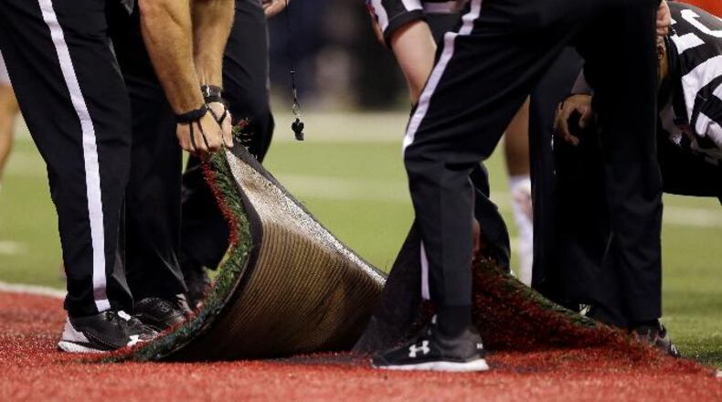 Officials pull up part of the artificial turf in the end zone to examine a during the second half of the Big Ten championship NCAA college football game between Wisconsin and Ohio State , Saturday, Dec. 2, 2017, in Indianapolis. (AP Photo/AJ Mast)