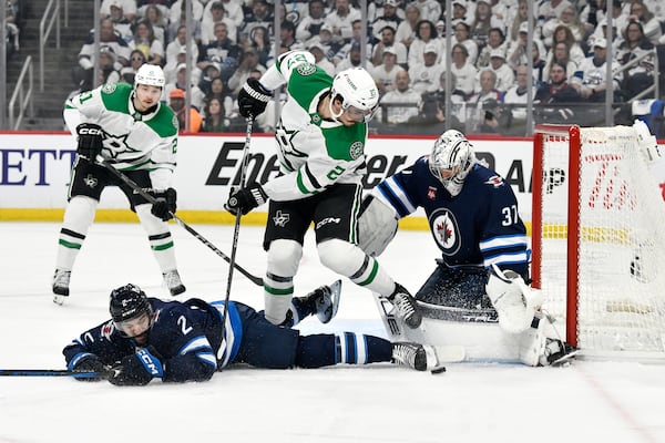 Winnipeg Jets goaltender Connor Hellebuyck (37) makes a save on Dallas Stars' Mason Marchment (27) as Dylan Demelo (2) defends during first period NHL playoff hockey action in Winnipeg, Thursday, May 15, 2025. (Fred Greenslade/The Canadian Press via AP)