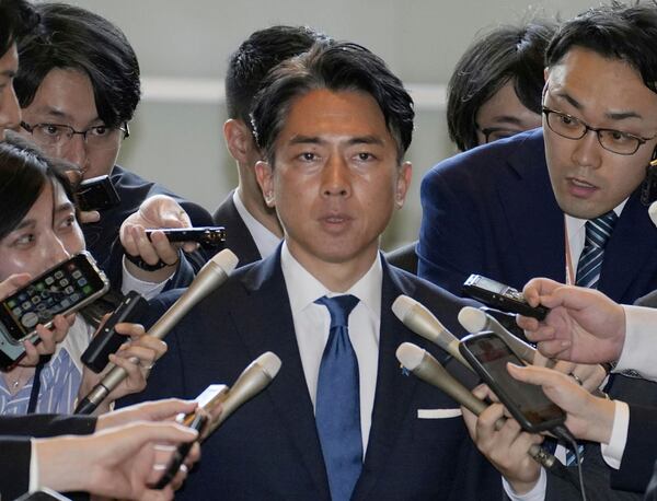 Former Environment Minister Shinjiro Koizumi, center, is surrounded by reporters at the prime minister's office in Tokyo Wednesday, May 21, 2025. (Kyodo News via AP)