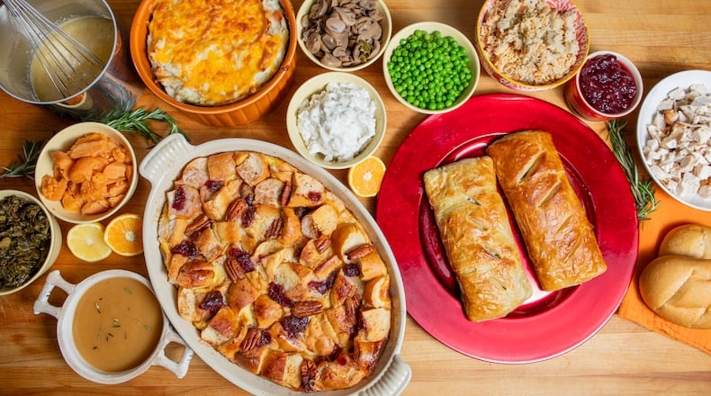 Give your Thanksgiving leftovers a new life by turning them into Cranberry Pecan Bread Pudding with Citrus Glaze (white oblong dish), Thanksgiving Strata (round orange dish) and Thanksgiving Wellingtons (red plate). (Aaliyah Man for The Atlanta Journal-Constitution)