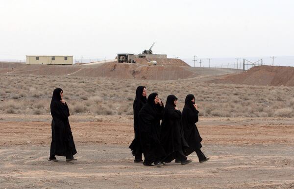 FILE - Iranian women walk past an anti-aircraft gun, at the conclusion of a rally to support Iran's nuclear programs, in front of the Natanz Uranium Enrichment Facility, some 200 miles (322 km) south of the capital Tehran, Iran, March 9, 2006. (AP Photo/Vahid Salemi, File)