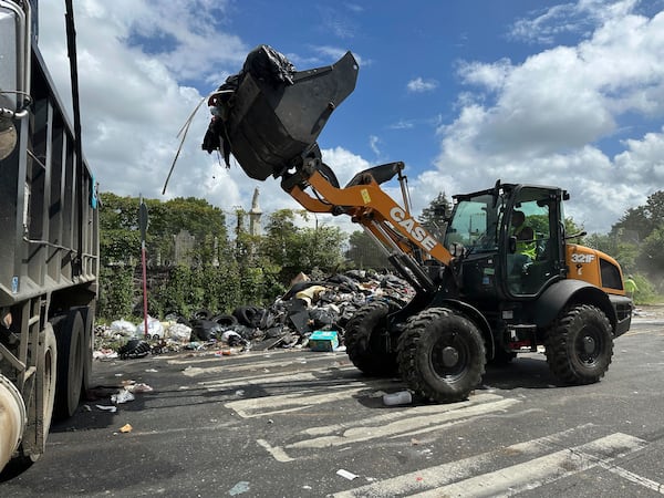 Trash is cleaned up at a drop-off site in Philadelphia as thousands of city workers remained on strike Monday, July 7, 2025. (AP Photo/Tassanee Vejpongsa)