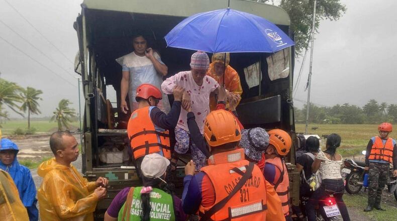 In this photo provided by the Philippine Coast Guard, rescuers evacuate residents in Sablayan, Occidental Mindoro province of the Philippines as Typhoon Fung-wong batters the country on Sunday, Nov. 9 2025. (Philippine Coast Guard via AP)