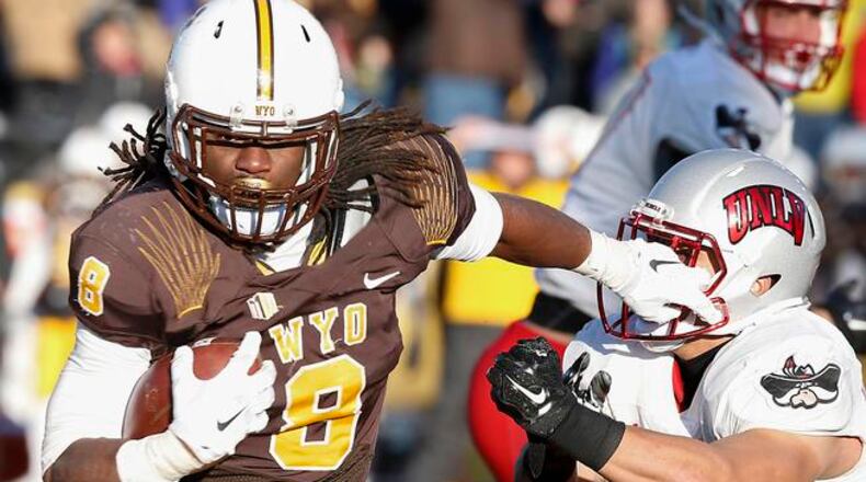 Wyoming running back Brian Hill stiff arms UNLV linebacker Matt Lea during the fourth quarter of an NCAA college football game, Saturday, Nov. 28, 2015, in Laramie, Wyo. (AP Photo/Michael Smith)