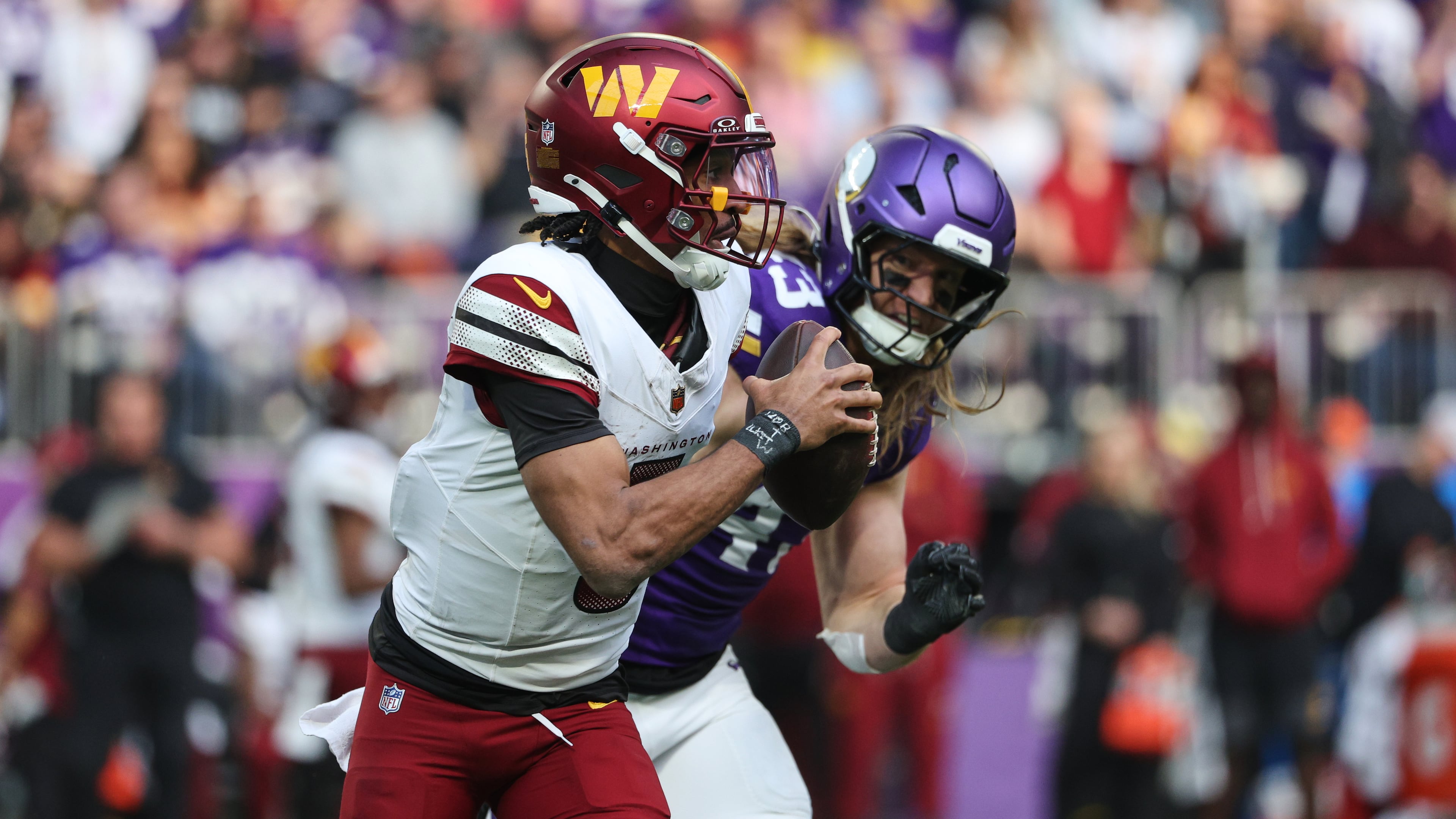 Washington Commanders quarterback Jayden Daniels (5) looks to pass while being chased by Minnesota Vikings linebacker Andrew Van Ginkel (43) during the first half of an NFL football game, Sunday, Dec. 7, 2025, in Minneapolis. (AP Photo/Matt Krohn)