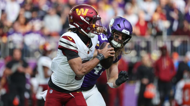 Washington Commanders quarterback Jayden Daniels (5) looks to pass while being chased by Minnesota Vikings linebacker Andrew Van Ginkel (43) during the first half of an NFL football game, Sunday, Dec. 7, 2025, in Minneapolis. (AP Photo/Matt Krohn)