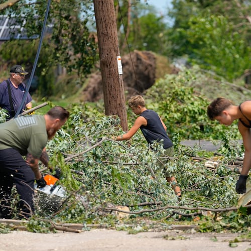 Volunteers help clear tree limbs near a damaged house after a tornado hit the day before in Appleton, Wis., Tuesday, July 28, 2026. (AP Photo/Kayla Wolf)
