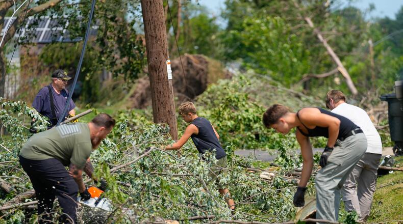 Volunteers help clear tree limbs near a damaged house after a tornado hit the day before in Appleton, Wis., Tuesday, July 28, 2026. (AP Photo/Kayla Wolf)