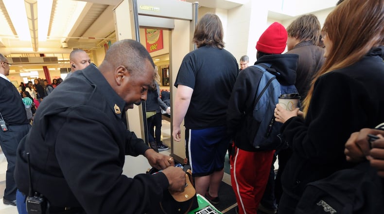 Master Sergeant Henry Bleach checks bags as students approach a metal detector at Grady High School on Thursday, March 7.