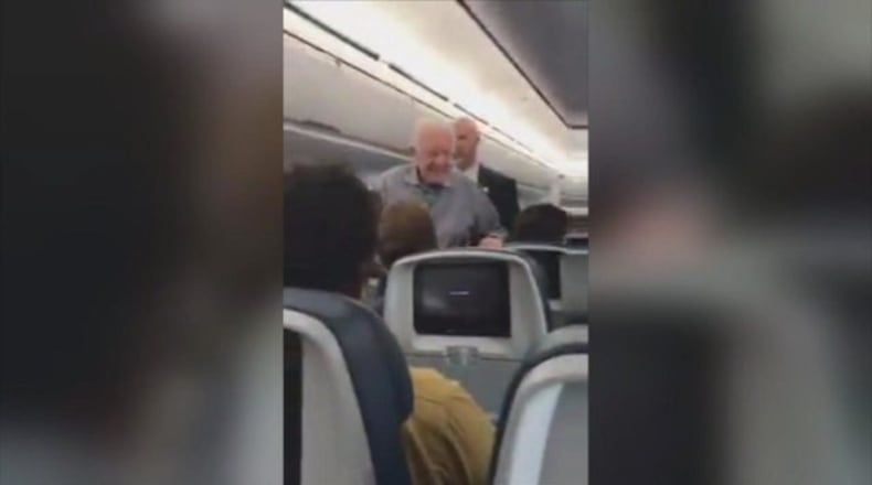 Former President Jimmy Carter works his way down the aisle, shaking passenger’s hands, on a flight last week.
