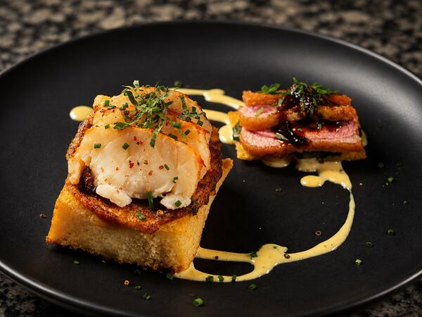 Seared seafood served over a rectangular toast base with vegetables and sauce.
