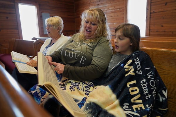 Sheri Taylor, left, sits with her daughter, Laura Wood, and granddaughter, Riley McKibbin, 11, while singing from "The Sacred Harp" in the tenor section at Holly Springs Primitive Baptist Church in Bremen, Ga., on Saturday, March 22, 2025. (AP Photo/Jessie Wardarski)