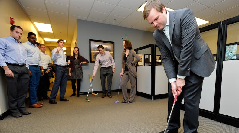 InsightSourcingGroup's Mike O'Brien putts a golf ball toward the cup on an indoor putting course during a happy hour event.