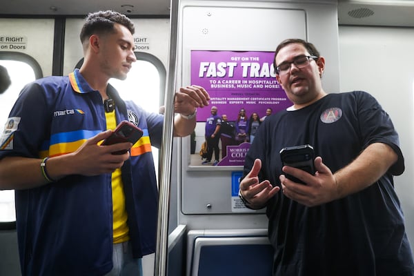 Joabe Barbosa talks to former MARTA rail supervisor Thomas Troxell, while attempting to set a Guinness World Record for the fastest time visiting every single MARTA station. Troxell has a live train tracker on his phone. (Abbey Cutrer/AJC)