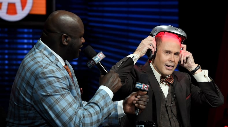 LAS VEGAS, NV - JANUARY 05: NBA analyst Shaquille O'Neal (L) looks on as TNT's Inside the NBA host Ernie Johnson Jr. puts on an iGrow laser-based hair-growth helmet during a live telecast of "NBA on TNT" at CES 2017 at the Sands Expo and Convention Center on January 5, 2017 in Las Vegas, Nevada. CES, the world's largest annual consumer technology trade show, runs through January 8 and features 3,800 exhibitors showing off their latest products and services to more than 165,000 attendees. (Photo by Ethan Miller/Getty Images)