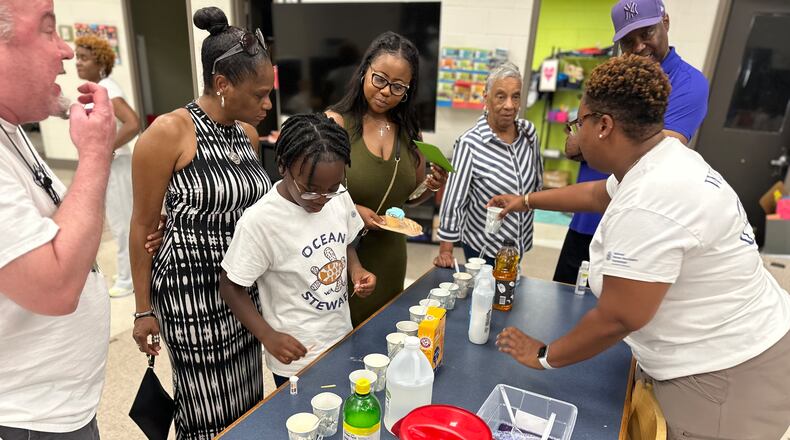 Kelli Edwards (right) talks with Westside Atlanta Charter students and parents about how to measure alkaline in ordinary household products. Courtesy