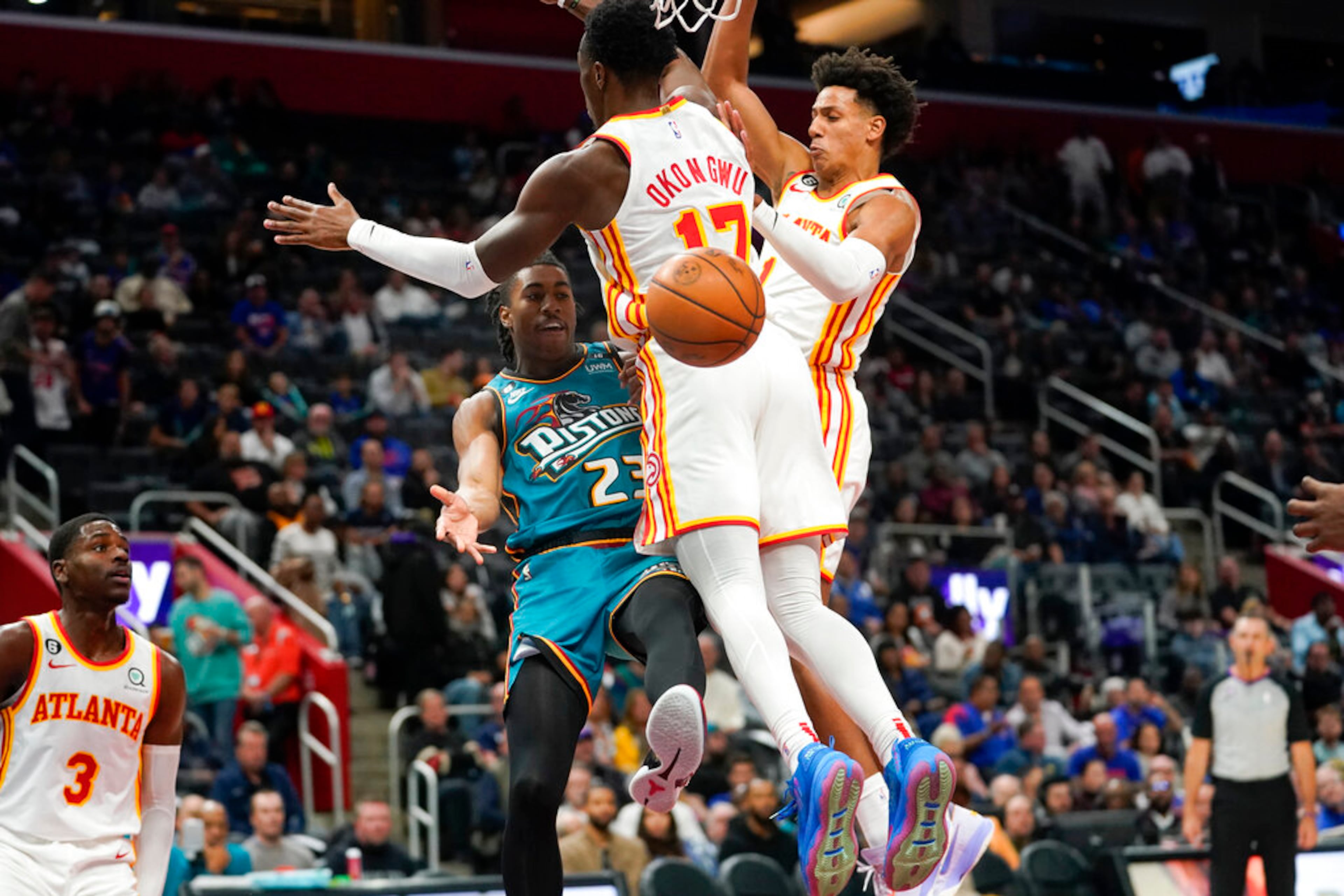 Pistons guard Jaden Ivey passes around Hawks Onyeka Okongwu and Jalen Johnson in the first half of a 2022 game in Detroit. (Paul Sancya/AP)