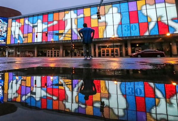 June 22, 2017 Atlanta: Kenny Brown walks by the pooling water from rain reflected the colorful facade of the College Football Hall of Fame at 250 Marietta St NW, in downtown Atlanta on Thursday, June 22, 2017.  JOHN SPINK/JSPINK@AJC.COM.