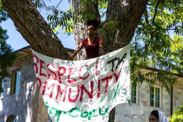 Student Elaini Asamere hangs a banner at a rally protesting Atlanta’s proposed public safety training center at Emory University in Atlanta on Monday, April 24, 2023. (Arvin Temkar / arvin.temkar@ajc.com)
