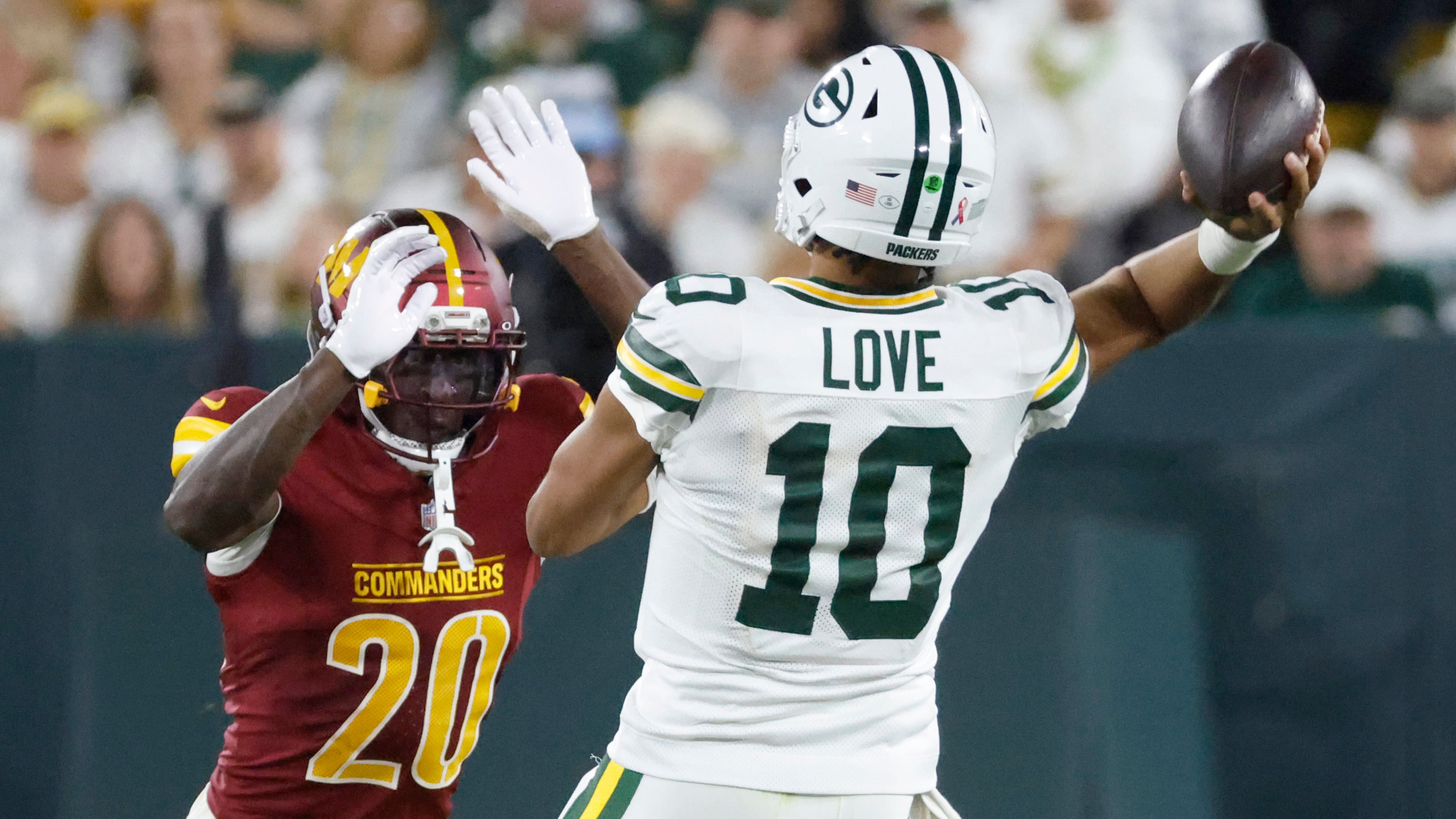 Green Bay Packers quarterback Jordan Love (10) throws under pressure from Washington Commanders safety Quan Martin (20) during the second half of an NFL football game Thursday, Sept. 11, 2025, in Green Bay, Wis. (AP Photo/Mike Roemer)