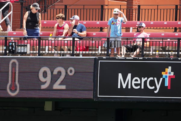 Fans in the bleachers try to stay cool in Busch Stadium before the start of a baseball game between the St. Louis Cardinals and the Cincinnati Reds Saturday, June 21, 2025, in St. Louis. (AP Photo/Jeff Roberson)