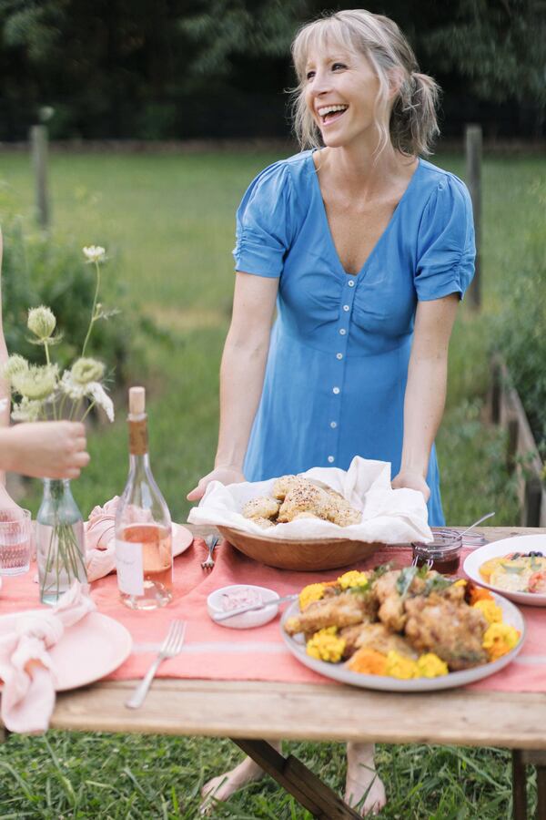 Chef Suzanne Vizethann stands behind an outdoor table set with food.