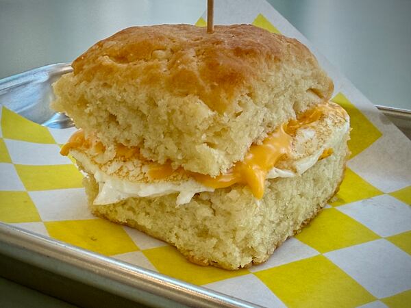 An egg and cheese breakfast sandwich on a square biscuit on a metal tray