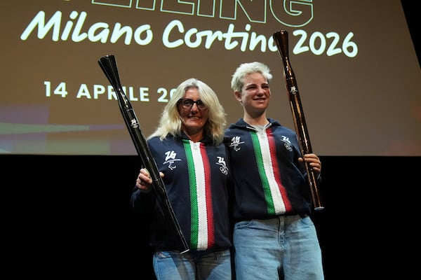 Former Italy's Cross Country skier Stefania Belmondo, right, and Paralympic champion Beatrice 'Bebe' Vio hold the Milano Cortina 2026 Winter Olympics and Paralympics torches during the unveiling ceremony in Milan, Italy, Monday, April 14, 2025. (AP Photo/Antonio Calanni)