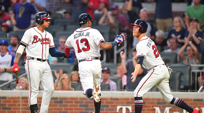 Mike Foltynewicz and Johan Camargo congratulate Ronald Acuna after Acuna scored   a third-inning run against the Colorado Rockies at SunTrust Park on Saturday.