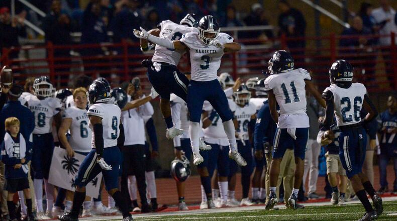 Marietta's Ezekial Durham-Campbell (left) and Peter Warrick (right) celebrate a turnover in the second half of Friday's Class AAAAAAA playoff game against Milton. (Daniel Varnado/Special)