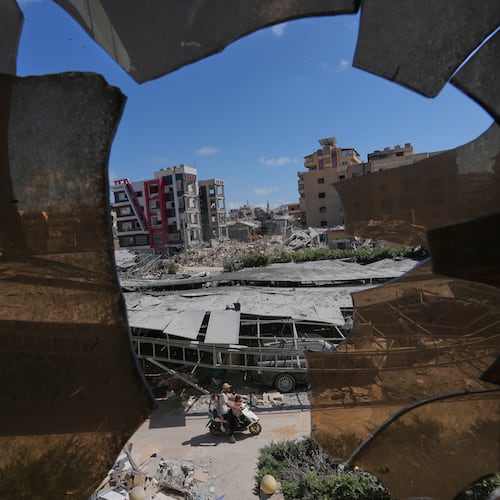 Buildings damaged by Israeli strikes are seen through shattered glass from the Jabal Amel Hospital in the southern port city of Tyre, Lebanon, Thursday, June 18, 2026. (AP Photo/Hassan Ammar)