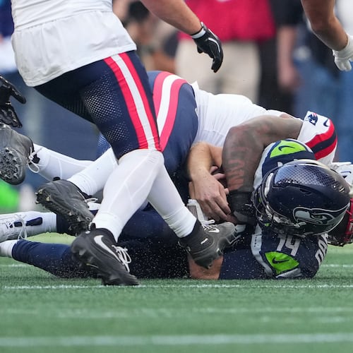 Seattle Seahawks quarterback Sam Darnold, (14) is sacked by New England Patriots linebacker Dre'mont Jones, behind, during the first half an NFL football game, Wednesday, Sept. 9, 2026, in Seattle. (AP Photo/Lindsey Wasson)