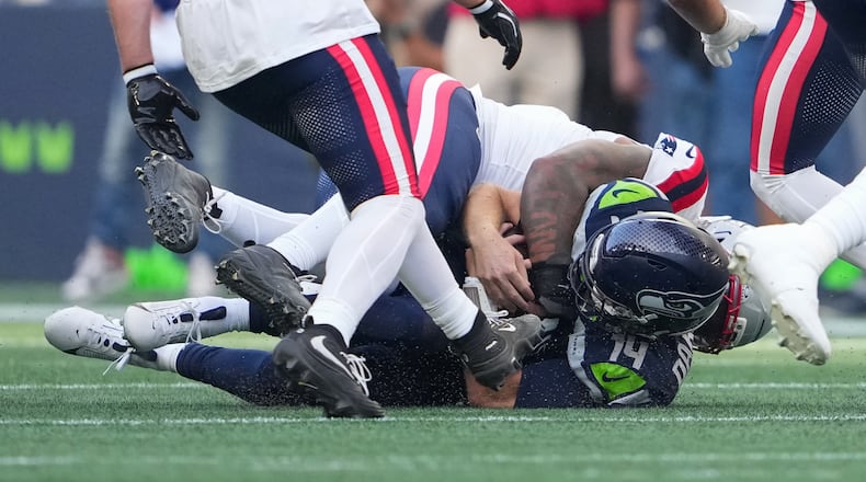 Seattle Seahawks quarterback Sam Darnold, (14) is sacked by New England Patriots linebacker Dre'mont Jones, behind, during the first half an NFL football game, Wednesday, Sept. 9, 2026, in Seattle. (AP Photo/Lindsey Wasson)