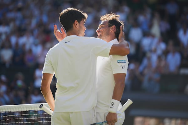 Carlos Alcaraz of Spain, left, greets Fabio Fognini of Italy at the net after winning their first round men's singles match at the Wimbledon Tennis Championships in London, Monday, June 30, 2025. (AP Photo/Alastair Grant)