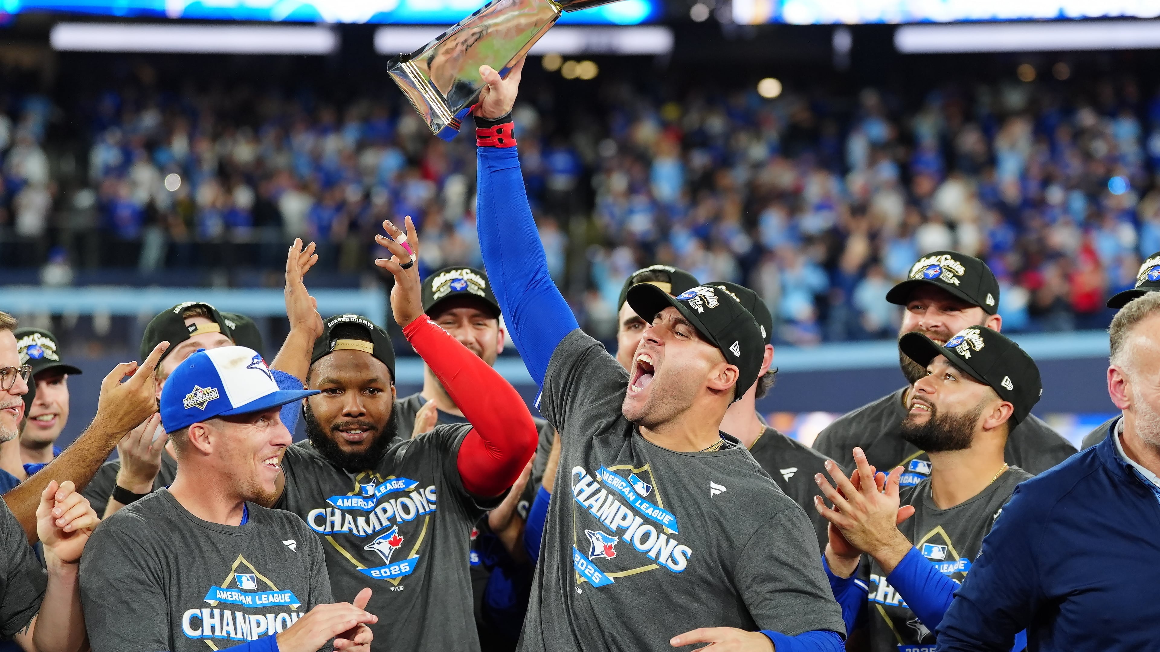 Toronto Blue Jays' George Springer holds the American League Championship Series trophy as the team celebrates after defeating the Seattle Mariners in Game 7 of the series in Toronto, Monday, Oct. 20, 2025. (Frank Gunn/The Canadian Press via AP)