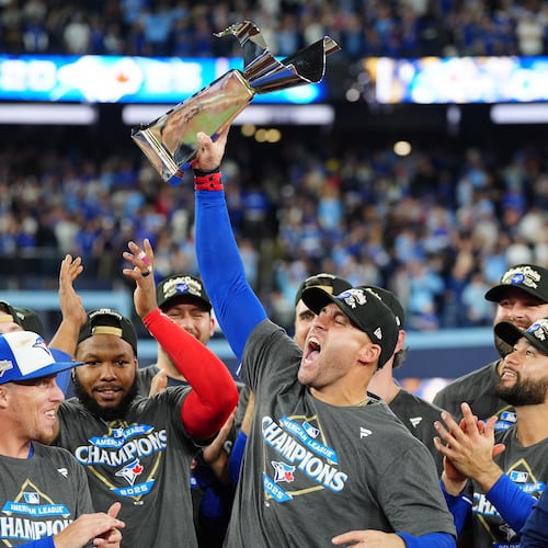Toronto Blue Jays' George Springer holds the American League Championship Series trophy as the team celebrates after defeating the Seattle Mariners in Game 7 of the series in Toronto, Monday, Oct. 20, 2025. (Frank Gunn/The Canadian Press via AP)