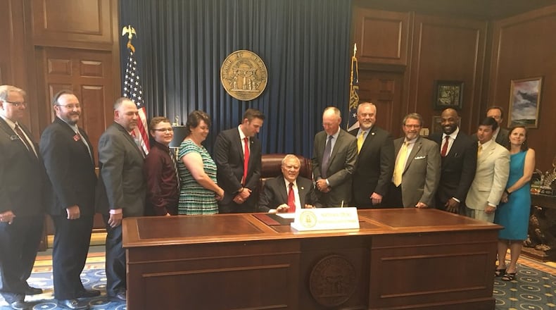 Gov. Nathan Deal signed House Bill 65 into law Monday to add PTSD and intractable pain to the list of conditions treatable by cannabis oil. State Rep. Allen Peake, the sponsor of the bill, is on Deal's right. They're surrounded by legislators and supporters. Photo credit: State Rep. Allen Peake