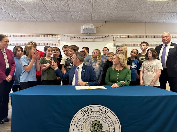 Students react as North Dakota Republican Gov. Kelly Armstrong hands a pen to a girl after he signed a bill for a "bell-to-bell" cellphone ban for public school K-12 students on Friday, April 25, 2025, at Centennial Elementary School in Bismarck, N.D. To the right of the governor is first lady Kjersti Armstrong. Republican Sen. Michelle Axtman is at left. Republican Rep. Jim Jonas is at right. (AP Photo/Jack Dura)