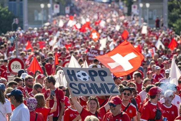 A fan holds a poster with the words in German "Go Switzerland" while walking with thousands to the stadium for he Women's Euro 2025 quarterfinal soccer match between Switzerland and Spain in Bern, Switzerland, Friday July 18, 2025. (Urs Flueeler/Keystone via AP)