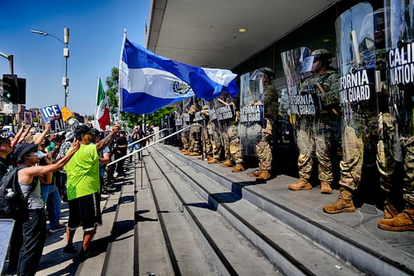 A protester waves a National Flag of El Salvador in front of a line of California National Guard in front of Federal Building on Monday, June 9, 2025, in downtown Los Angeles. (AP Photo/Eric Thayer)