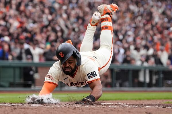 San Francisco Giants' Heliot Ramos scores the game-winning run on a throwing error Texas Rangers first baseman Jake Burger during the ninth inning of a baseball game Sunday, April 27, 2025, in San Francisco. (AP Photo/Godofredo A. Vásquez)