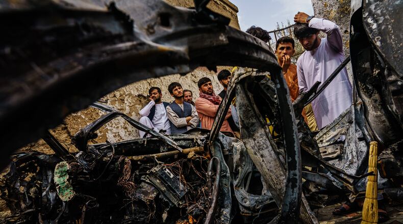Relatives and neighbors of the Ahmadi family gathered around the incinerated husk of a vehicle that the family says was hit by a U.S. drone strike, in Kabul, Afghanistan on Aug. 30.
