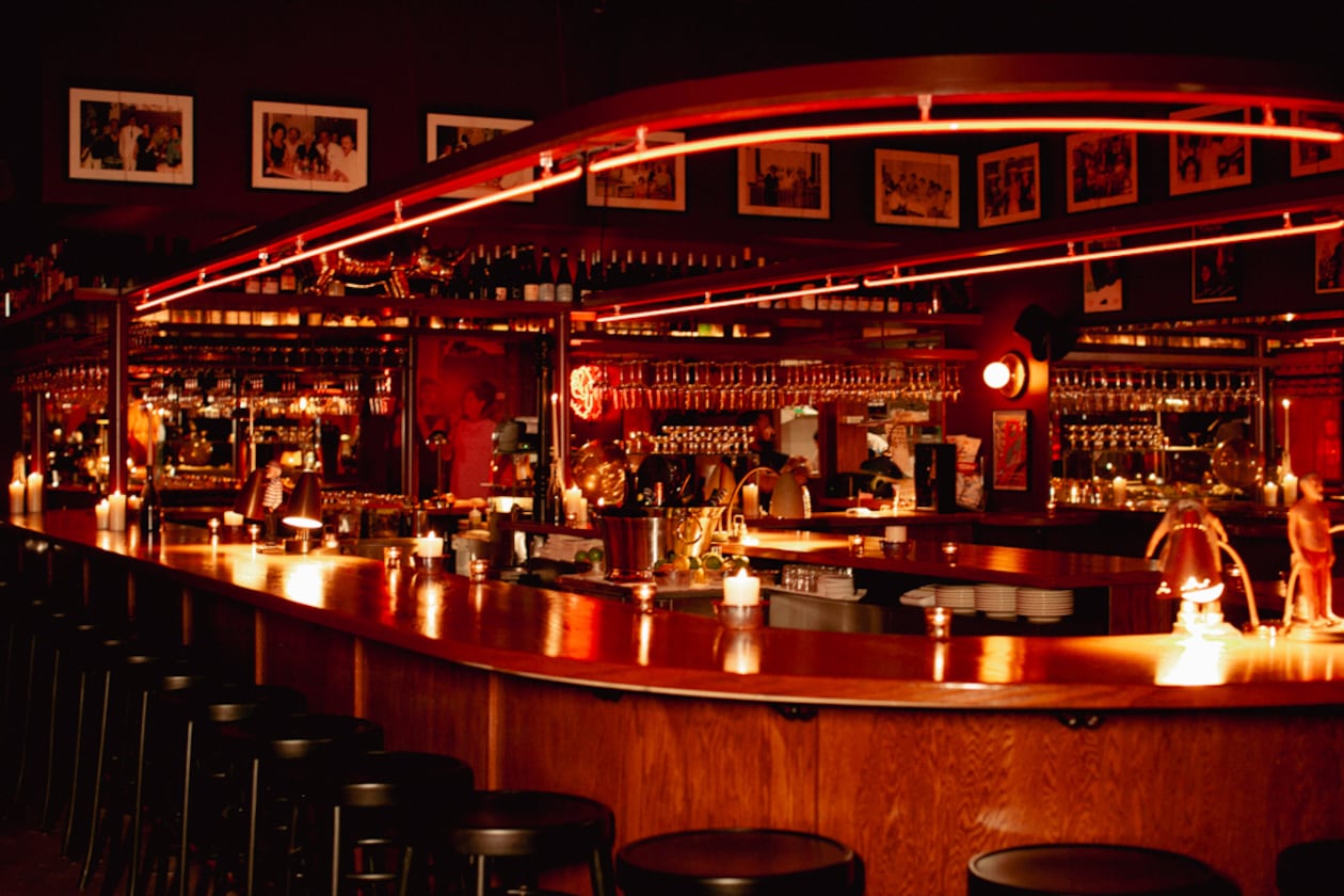 A U-shaped bar is lined by black bar stools and lit in red neon lights.