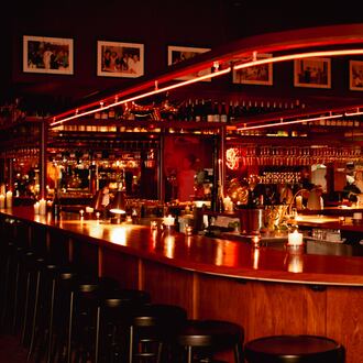 A U-shaped bar is lined by black bar stools and lit in red neon lights.