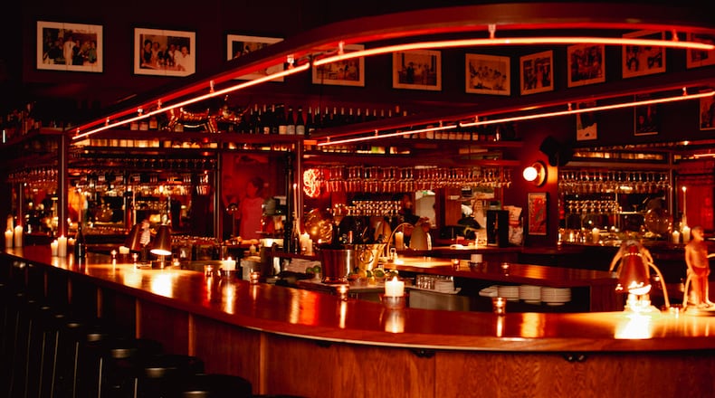 A U-shaped bar is lined by black bar stools and lit in red neon lights.