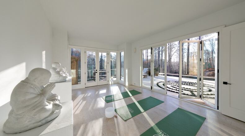 Designer Dana Lynch selected an all-white color palette to bring a sense of tranquility to the yoga room of a Serenbe home that looks onto a custom labyrinth and pool. PHOTO CREDIT: J Ashley Photography