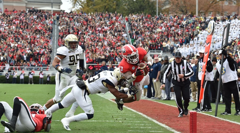 Georgia running back Elijah Holyfield (13) falls into the endzone past Georgia Tech defensive back Jaytlin Askew (33) for a touchdown during the first half in a NCAA college football game at Sanford Stadium on Saturday, November 24, 2018. HYOSUB SHIN / HSHIN@AJC.COM